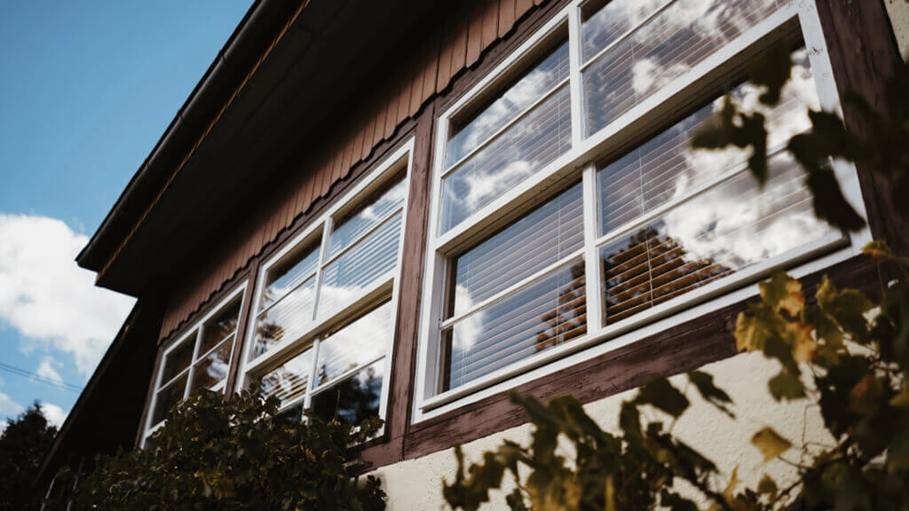 A house with large windows, showing reflection of the sky and trees.