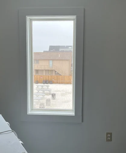 A close-up of a clean window showing a view of a beach and outdoor seating area.